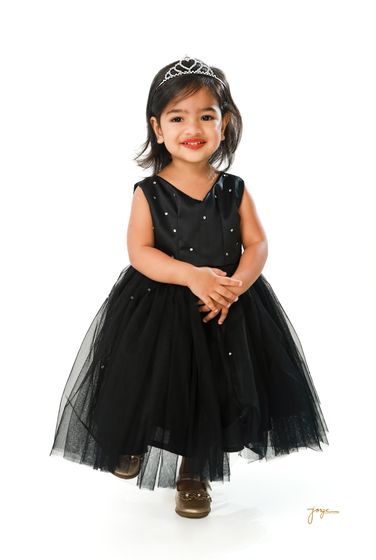 A little girl in a black tulle dress and crown