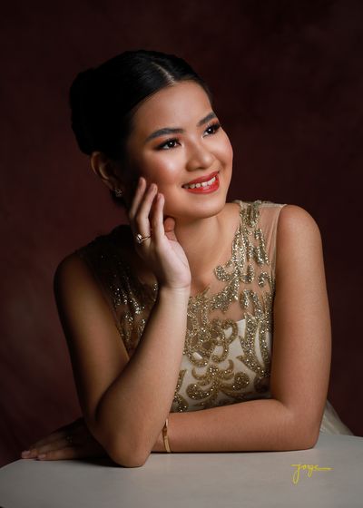 A debutante in a beaded gown resting her chin on her hand