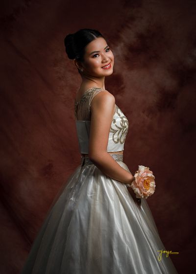 A debutante in a silver gown holding a bouquet