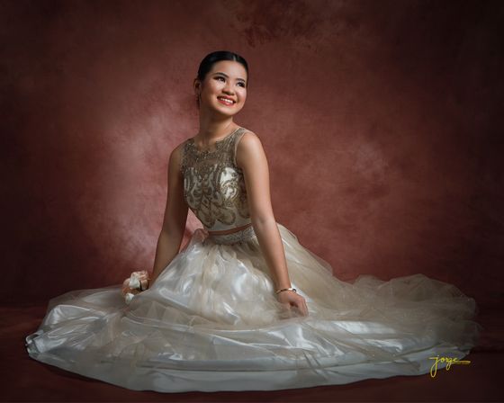 A debutante sweeping the train of her gown across the studio floor