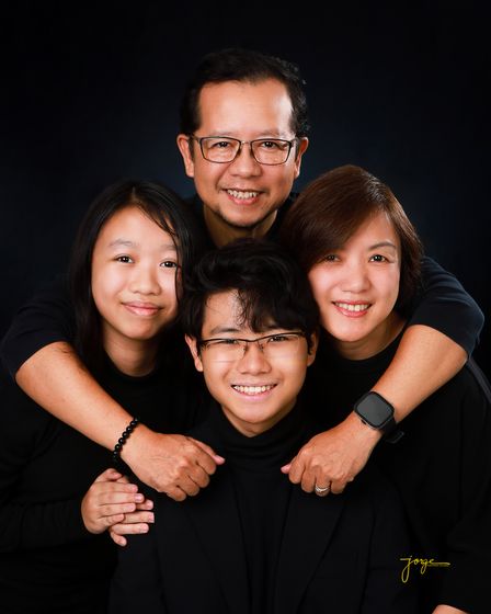 A family holding each other close, laughing, on black