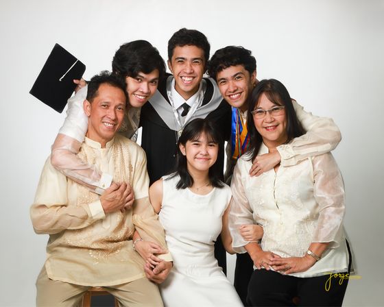 A large family in cream and white gathered for a graduation portrait