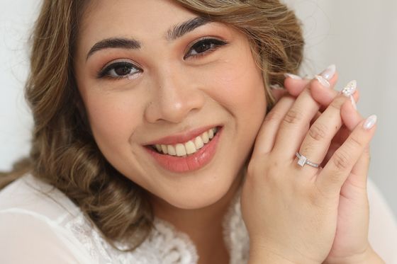 A close portrait of a bride resting her hands beneath her chin
