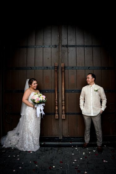 A couple standing before tall wooden church doors