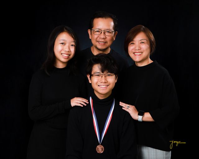 A family of four in matching black, photographed in the studio